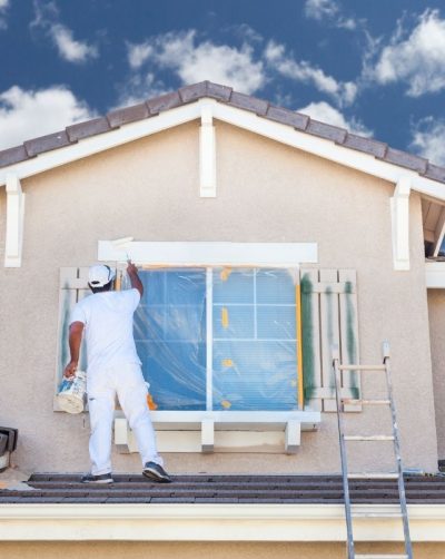 Professional House Painter Painting The Trim And Shutters Spraying Paint On Exterior of Old Home